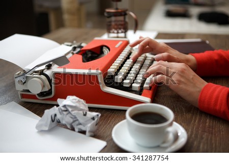 Side view of red typewriter, cup of coffe, crumpled paper