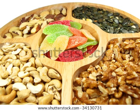 sunflower seeds, brazil nuts, caqshew nuts and colored slices of pineapples on wooden plate