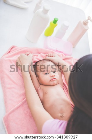 portrait of a mother happily playing with her baby after having bathed