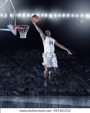 Athletic African American Basketball Player scoring a layup basket during a professional basketball game in a crowded arena