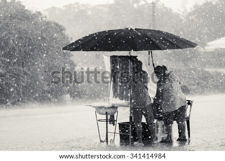 Two persons endure struggle on obstacles rainstorm - black white tone, unfocused