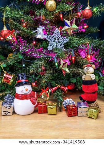Christmas tree and Snowman ceramic doll with gift box and decorations for background.