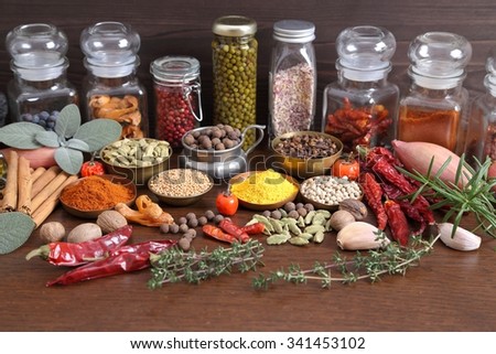 Flavorful, colorful spices in metal  bowls and glass bottles on dark wooden background.