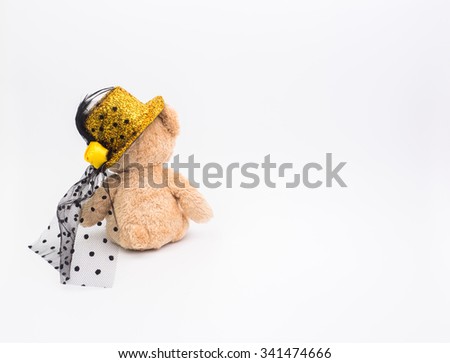 Back view of teddy bear with golden hat on white background