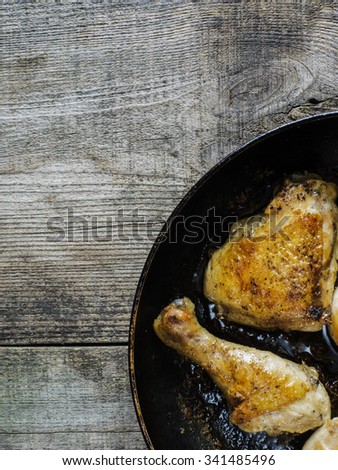 Roasted chicken thighs in a pan on old weathering wooden table