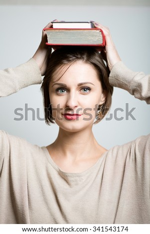 cute girl student with books on her head, lifestyle, photo studio on isolated gray background