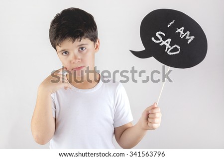 sad child holding a sign in his hand on a white background