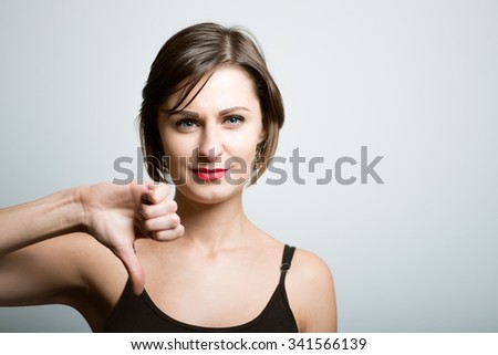 Pretty slim girl showing thumb down sign, lifestyle, isolated on a gray background