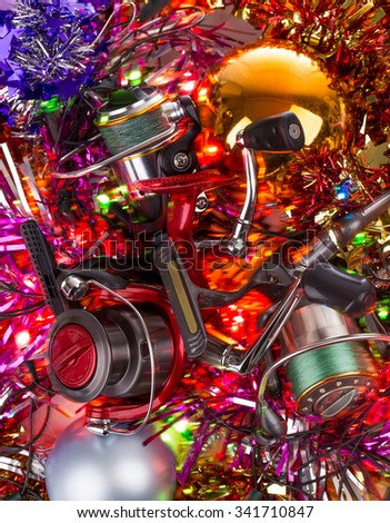 christmas and new year a postcard for fishers and anglers. fishing reel on bright spangles and ball background with blur