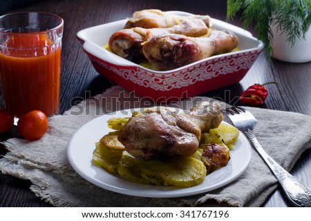 chicken drumsticks with baked potatoes on a dark background