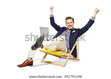 Concept shot of satisfied young man sitting on sunbed. He raises his arms in a gesture of victory.