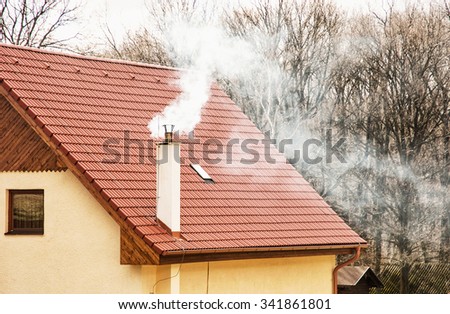 Smoking chimney on the red roof. Seasonal scene. Rural house. Royalty-Free Stock Photo #341861801
