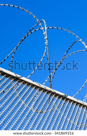 Fence with a barbed wire against the blue sky. Illustration of the concept of freedom or liberty.