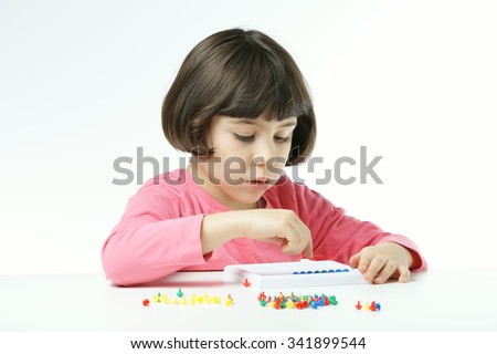 little girl is playing with Mushroom Nails pegboard on a white background, dressing a pink shirt