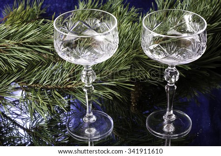 Christmas glasses on the background of spruce branches. On a blue background.