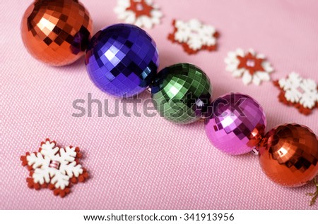 Multi-colored Christmas balls and snowflakes on a pink background.