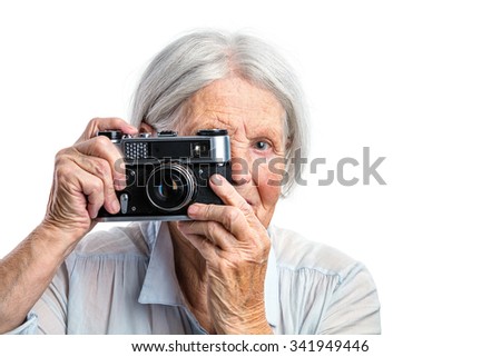 Senior woman shooting with a retro camera over white background