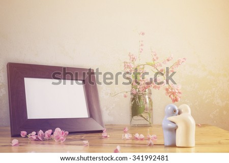 Still life with flowers and white photo frame on wooden table over grunge background. Valentine concept