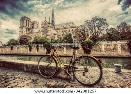 Retro bike next to Notre Dame Cathedral in Paris, France and the Seine river. Vintage Royalty-Free Stock Photo #342081257