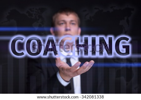 Businessman holding on the right hand a glowing text "Coaching". Business concept. Internet concept