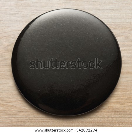 Blank black round badge on wooden background