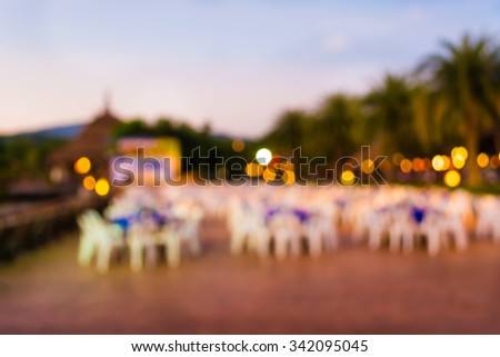 blur image of Tables and decoration prepared for an outdoor party on evening time for background usage.