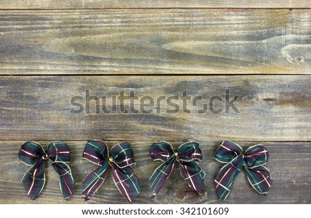Purple, green and gold Christmas bows border on antique rustic wood background