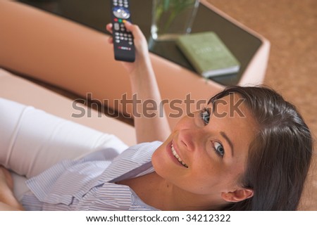 Young attractive woman sitting on couch watching TV