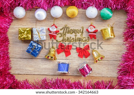 Xmas day: Merry Christmas decoration with gift box, ball, bell, drum, bow, tassel and santa claus doll on wood background. Top view.