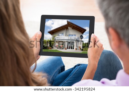 Close-up Of Mature Couple Looking At House Photo On Digital Tablet