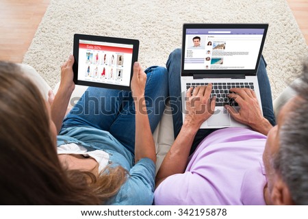 High Angle View Of Couple Online Shopping And Chatting On Computers