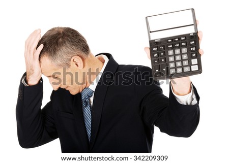 Depressed mature businessman holding a calculator.