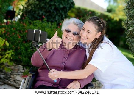 elderly senior woman on wheelchair with nurse outdoor in nursing home hospital garden