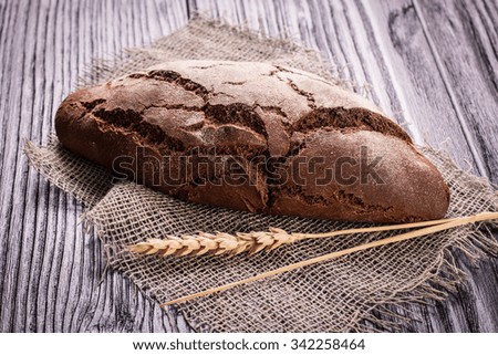 Rustic bread and wheat on an old vintage planked wood table. Dark moody background with free text space.