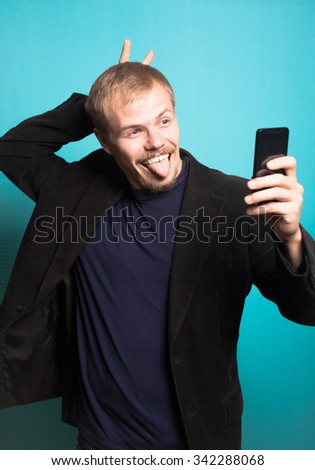 successful business man making funny self image, with a beard and mustache, office style studio photo isolated on a blue background