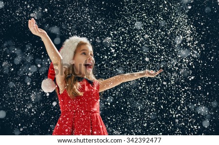 a Christmas miracle! happy little girl catching snowflakes in her hands