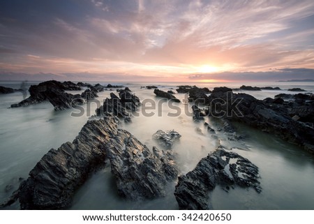 sunrise at rocky beach in terengganu, malaysia. image taken with long exposure,custom white balance