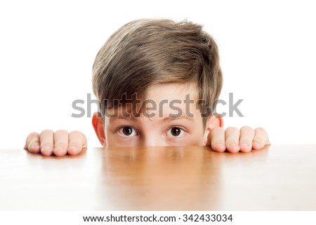 ? timid boy peeks out from under the table Royalty-Free Stock Photo #342433034