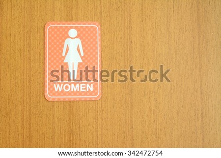Woman toilets sign for public restroom on a wood wall.