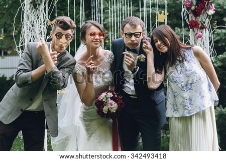 elegant stylish happy guests and bride and groom having funny photos on the background of arch, photo booth Royalty-Free Stock Photo #342493418