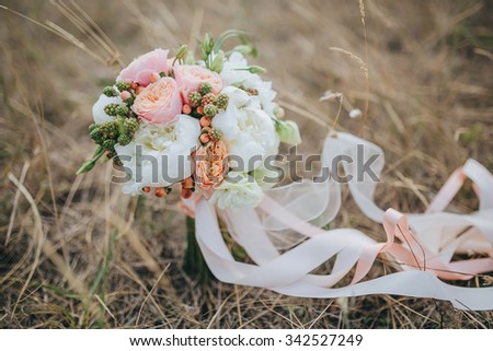 bouquet of pink and white flowers with green lying on the dry grass in the field