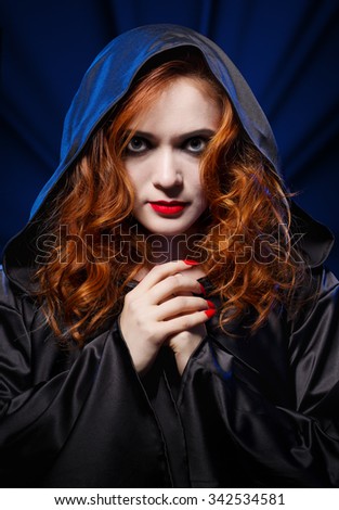 Young witch on blue light background