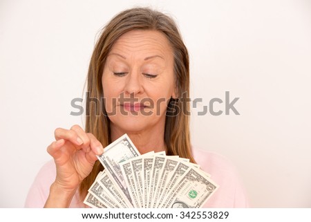 Portrait happy attractive mature woman holding US dollar notes, isolated, bright background.