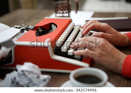Side view of red typewriter, cup of coffe, crumpled paper