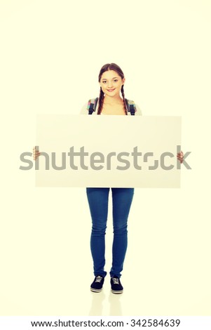 Happy teenage woman with blank billboard.
