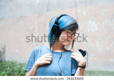Young woman with headphones and mobile phone smiling while listening music