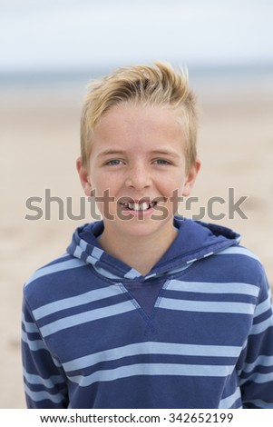 Portrait of a happy teenage boy at the beach. He is wearing casual clothing and smiling at the camera. 