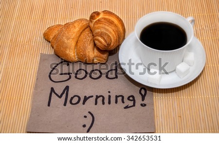 Text Good morning on paper with coffee and croissant