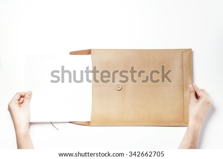 A woman(girl, female) hands hold(write) a luxury brown leather envelope with a empty(blank, vacant, hollow) paper isolated white at the studio.