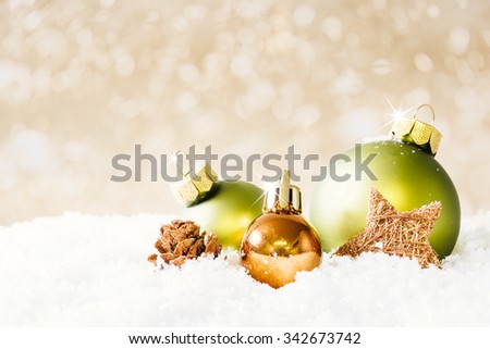 A fire cone and three christmas balls on snow with soft beige  bokeh background. Selected focus, narrow depth of field.